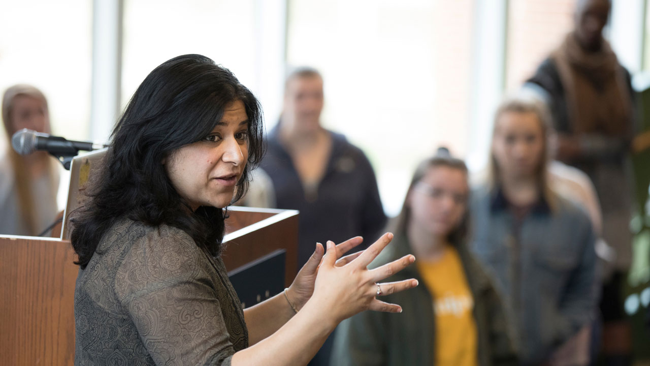 A professor gestures as she speaks to a group of students