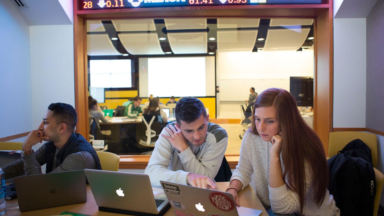 Students work on their laptops in the study room outside the Financial Technology Center.