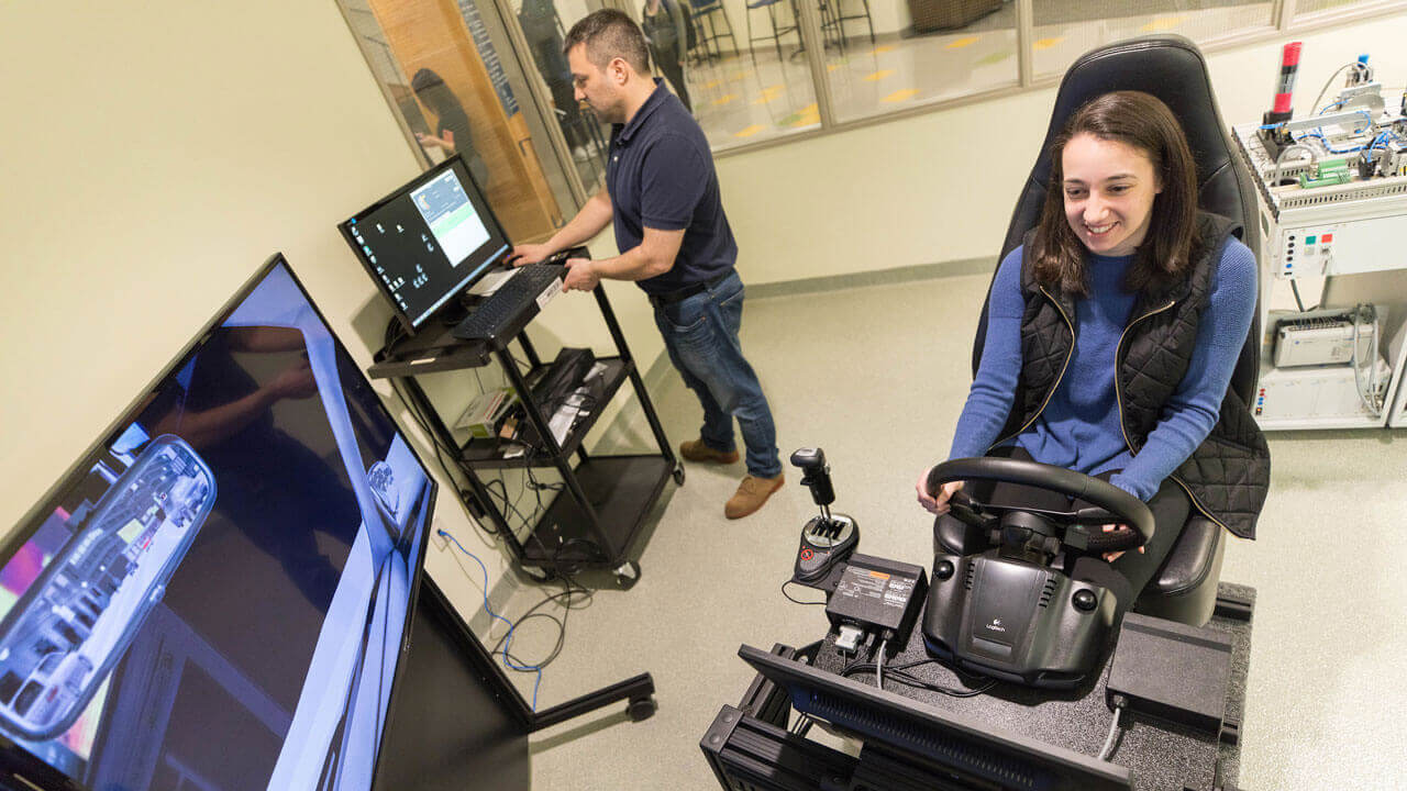 A student working with the School of Engineering's car simulator