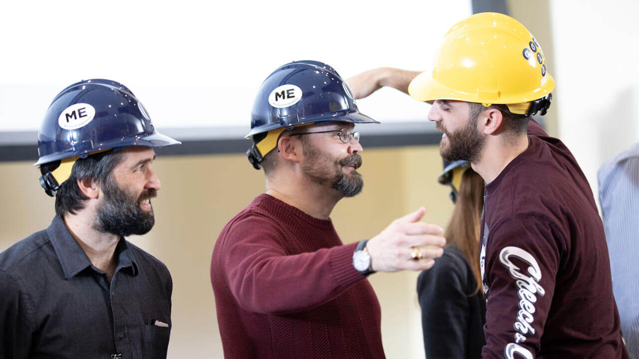 A student embraces a professor during the hard hat ceremony